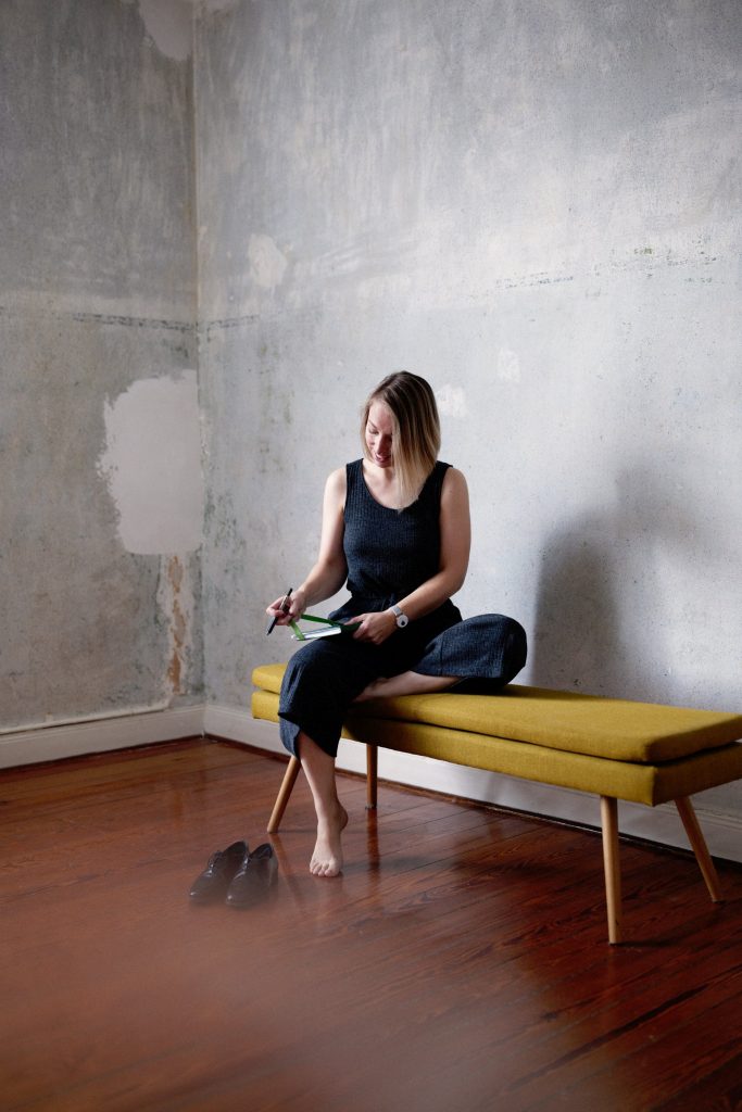 Jana Montasser sitzt auf einem Sofa und notiert Gedanken